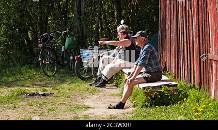 Umea, Norrland Schweden - 10. Juni 2020: Touristen und Einheimische sitzen und beobachten den schönen Fluss Stockfoto