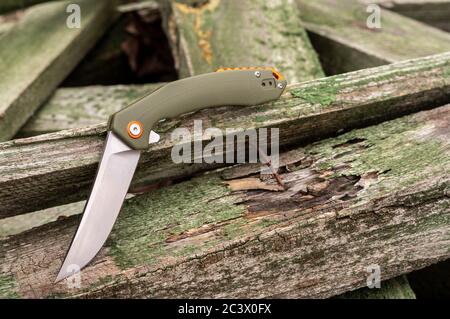 Messer in gebogener Position auf Holzbrettern. Ungewöhnliche Form eines Messers. Scharfes Messer. Stockfoto