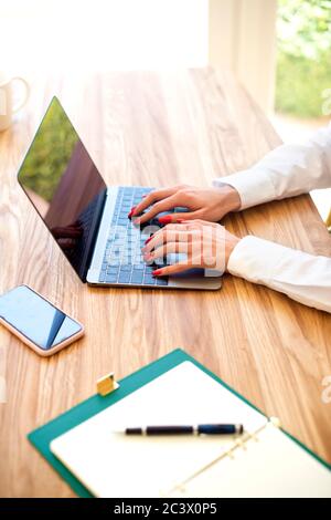 Nahaufnahme der Hand einer Geschäftsfrau bei der Arbeit am Laptop. Unerkannte Frau, die am Schreibtisch sitzt und auf der Tastatur tippt. Stockfoto