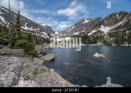 Lake Haiyaha im Rocky Mountain National Park während des Mittags mit untergetauchten Felsen und Farben, entfernten Bergen und einem dramatischen Himmel Stockfoto