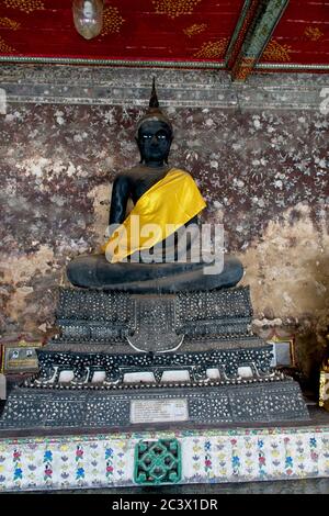 Wat Suthat Tempel, Gebäude und Meditation Bhudda Statuen Hochformat von schwarz gemaltem Buddha mit gelbem Tuch über der linken Schulter Stockfoto