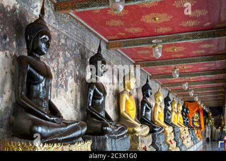 Wat Suthat Tempel, Gebäude und Meditation Bhudda Statuen. Reihe von sitzenden schwarz und Gold vergoldeten buddha-Symbole unter der Abdeckung zurücktreten von vorne nach hinten Stockfoto