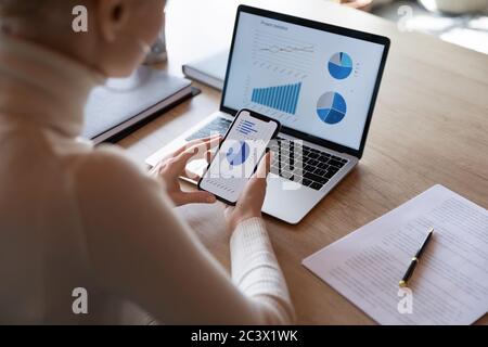 Geschäftsfrau mit Smartphone und Laptop, Verkaufsstatistiken auf Geräten Bildschirme Stockfoto