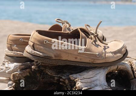 Ein Paar gut getragene Deckschuhe auf einem Treibholz-Baumstamm am Strand Stockfoto