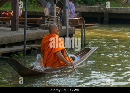 Bhudist Mönche und Einheimische auf Bangkok schwimmenden Markt. Ein Mönch paddelt traditionelles Boot aus dem Bild bewegt Stockfoto