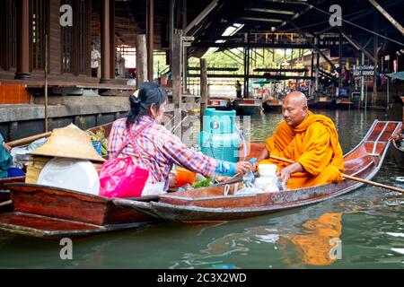 Bhudist Mönche und Einheimische in Bangkoks schwimmenden Markt Frau und Mönch in einem Boot jeder nebeneinander Gasbehälter Im Boot der Frau Stockfoto