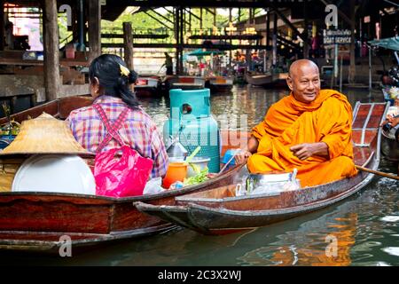 Bhudist Mönche und Einheimische in Bangkoks schwimmenden Markt Frau und Mönch in einem Boot jeder nebeneinander Gasbehälter Im Boot der Frau Stockfoto