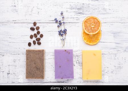 Oben über der Ansicht Foto von handgefertigten Bio-Seife Bars mit Kaffeebohnen Lavendel und getrockneten Orangenscheiben isoliert auf weißem Holzhintergrund Stockfoto