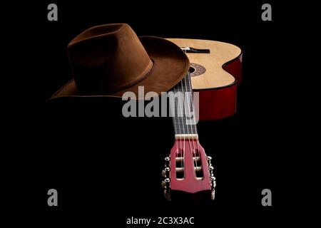 Amerikanische Kultur, Volkslied und Country Muisc Konzept Thema mit einem Cowboy Hut und eine akustische Gitarre isoliert auf schwarzem Hintergrund mit dramatischen Lightti Stockfoto