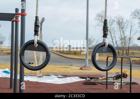 Metallene Gymnastikringe hängen auf dem Outdoor-Sportplatz, der repariert und restauriert wird Stockfoto