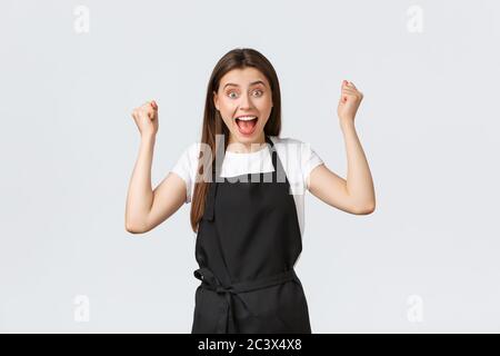 Lebensmittelgeschäft Mitarbeiter, kleine Unternehmen und Cafés Konzept. Glückliche weibliche Barista in schwarzer Schürze, die Hände hochhebt in Jubele, feiert groß Stockfoto