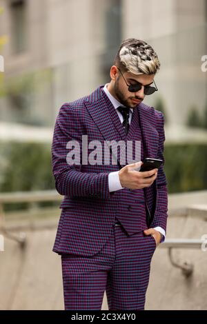 Geschäftsmann Außerhalb Büro Auf Handy. Mann trägt in violetten Luxus dreiteiligen Anzug Stockfoto