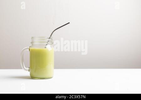 Matcha grüner Tee Latte in Glas mit Metallrohr auf weißem Hintergrund Stockfoto