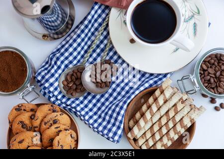 Weiße Tasse Kaffee und hausgemachte runde Plätzchen mit Schokoladenchips. Das Frühstück ist auf dem Tisch. Essen zu Hause. Stillleben. Kaffee und Kaffeebohnen. Ein Stockfoto