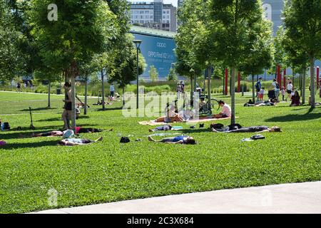 Mailand, Italien 06.20.2020: Menschen üben Yoga und genießen die Sonne in sozialen Distanzierungsskalen auf dem Gras in der neuen Bibliothek der Bäume par gemalt Stockfoto