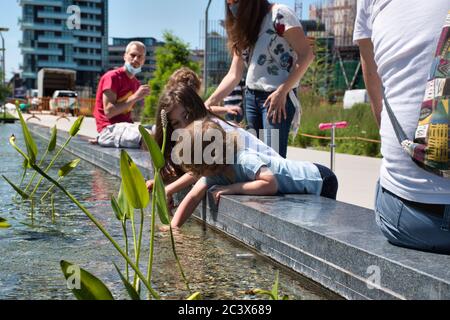 Mailand, Italien 06.20.2020: Kinder genießen die Sonne und spielen mit dem Wasser im neuen Park der Baumbibliothek in Mailand Stockfoto