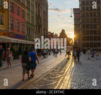Breslau, Polen - 16. August 2019: Menschen, die bei Sonnenuntergang am Marktplatz der Stadt in der Altstadt spazieren gehen. Stockfoto
