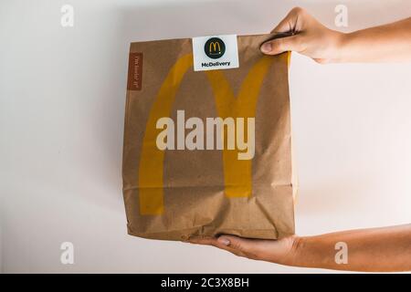 Lviv / Ukraine - April 2020: Zwei Hände geben einen Papierbeutel mit McDonalds Essen zum Mitnehmen. Ungesunde Ernährung zu Hause während Coronavirus Ausbruch Isolation Stockfoto