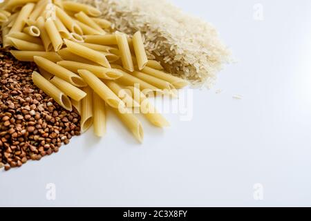 Ganze Körner auf weißem Tisch. Roher Buchweizen, Nudeln, Reis. Leerer Speicherplatz für Kopie. Panik beim Kauf von Lebensmitteln in großen Mengen für Coronavirus-Ausbruch Isolation Stockfoto