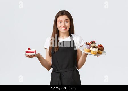 Lebensmittelgeschäft Mitarbeiter, kleine Unternehmen und Cafés Konzept. Freundliche lächelnde Kellnerin im Cafe hält Teller mit Cupcakes und Cafe, serviert Stockfoto