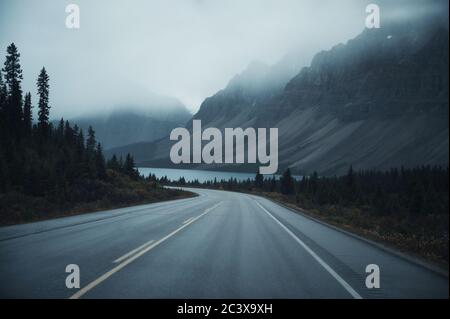 Geheimnisvolle Roadtrip mit felsigen Bergen in nebelig auf düster im Banff Nationalpark, Kanada Stockfoto