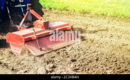 Traktor mit Fräsmaschine löst, schleift und mischt gemahlen. Feldvorbereitung für die Neubepflanzung. Anbaugeräte. Schleifen und Lösen Stockfoto