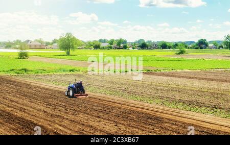 Bauer auf einem Traktor mit Fräsmaschine löst, schleift und mischt den Boden. Ackerboden für weitere Pflanzung. Lockern, Verbesserung der Bodenqualität Stockfoto