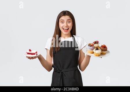 Lebensmittelgeschäft Mitarbeiter, kleine Unternehmen und Cafés Konzept. Freundliche lächelnde Kellnerin im Cafe hält Teller mit Cupcakes und Cafe, serviert Stockfoto