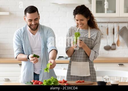 Glückliches Paar lachend hält grüne Gurke in den Händen. Stockfoto