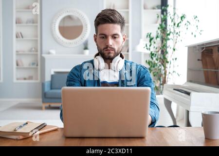 Schöner moderner Mann Designer arbeitet auf Laptop online, mit Internet zu Hause Stockfoto