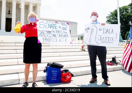 Ein Mann und eine Frau tragen Gesichtsmasken, während sie ihre Plakate während der Demonstration zeigen.Pro-DACA (Deferred Action for Childhood Arrivals) Demonstration vor dem Obersten Gerichtshof. Der Zweck der Kundgebung war es, die Entscheidung des Obersten Gerichtshofs in der vergangenen Woche über DACA zu feiern und auf eine dauerhafte Lösung zu drängen. Die Glocken wurden in sieben Minuten-Intervallen geläutet, um die 700,000 DACA-Empfänger zu ehren, die von der Entscheidung des Obersten Gerichtshofs betroffen waren. Stockfoto