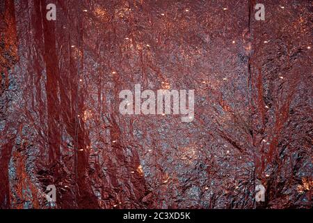 Rot-goldener metallischer Hintergrund mit rumpeltem Folienhintergrund und glänzenden Lichtern. Glitzer-Textur aus gefaltetem Metallic-Gewebe. Heller Schimmer Weihnachten glühenden Hintergrund. Stockfoto