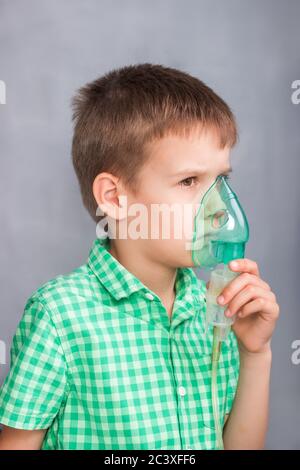 Junge halten Maske des Verneblers und macht Inhalation Stockfoto