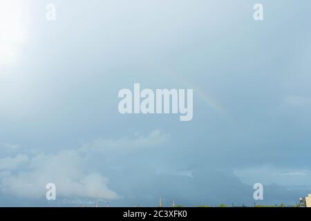 Weicher Regenbogen im blauen Himmel über der Stadt Stockfoto