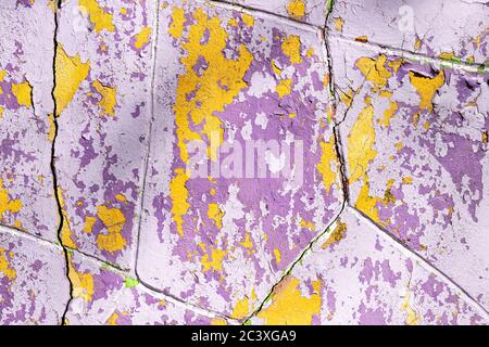 Textur von abblätternder lila und gelber Farbe auf alter Wandoberfläche. Gebäudefassade mit beschädigter Farbe. Abstrakter Hintergrund, Nahaufnahme. Stockfoto