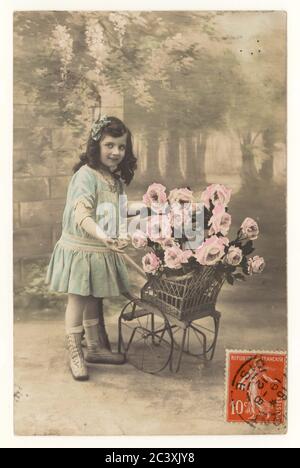 Anfang des 20. Jahrhunderts sentimentale französische Postkarte von jungen Mädchen mit Schubkarre voller Rosen, postciled 19 Aug 1912, Frankreich Stockfoto