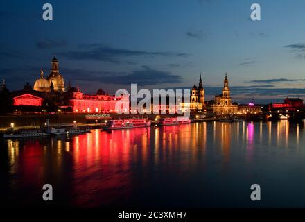 Dresden, Deutschland. Juni 2020. Das Lipsiusgebäude (l), die Akademie der Künste und die Salonschiffe der Schächsischen Dampfschiffahrt sind abends rot beleuchtet, dahinter die Frauenkirche (l-r), das Ständehaus, der Hausmannsturm und die Hofkirche. Sachsen beteiligt sich an der bundesweiten Kampagne "Nacht des Lichts". In der Nacht zum 23. Juni werden Veranstaltungsorte und ausgewählte Gebäude in ganz Deutschland rot beleuchtet, um auf die dramatische Situation der Corona-Pandemie in der Eventbranche aufmerksam zu machen. Quelle: Robert Michael/dpa-Zentralbild/dpa/Alamy Live News Stockfoto