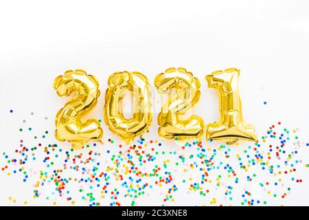 Frohes neues Jahr 2021 Feier. Gold Folie Ballons Zahl 2021 und Konfetti auf weißem Hintergrund. Flaches Lay Stockfoto