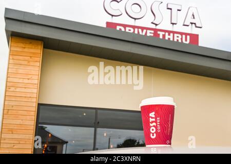 Talbot Green, Wales - Juni 2020: Tasse Kaffee auf dem Dach eines Autos vor einem Schild auf einem Costa Coffee Shop mit einer Durchfahrt. Stockfoto