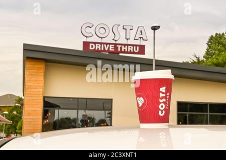 Talbot Green, Wales - Juni 2020: Tasse Kaffee auf dem Dach eines Autos vor einem Schild auf einem Costa Coffee Shop mit einer Durchfahrt. Stockfoto