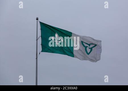 Die Franco-Ontarian Flagge fliegt auf einem Fahnenmast im Freien und zeigt die Fleur-de-lys und trillium Symbole, um Französisch Erbe und Ontario zu repräsentieren. Stockfoto