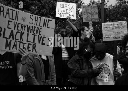 Demonstranten halten Plakate "Black Lives Matter", "Rain or Shine Everywhere BlackLivesMatter"during die Protestversammlung in Solidarität mit BLM Bewegung. Stockfoto