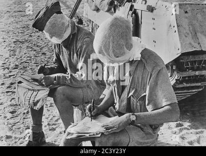 Zwei britische Soldaten mit ihren Köpfen von Moskitonetzen bedeckt, sitzen in der Nähe von Tank Schreiben Briefe, Western Desert, Ägypten, British Official Photo, 1942 Stockfoto