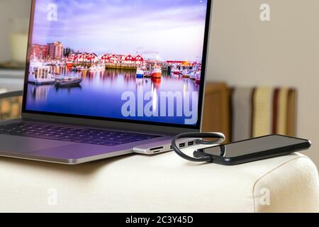 Smartphone wird aufgeladen, verbunden mit einem Hub-Adapter auf einem Laptop Stockfoto