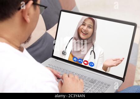 Konzept der Online-medizinischen Gesundheitsdienstleistungen, zeigt Laptop-Display mit asiatischen muslimischen Ärztin lächeln, telemedizinische Videoanruf Stockfoto