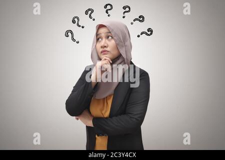 Schöne asiatische muslimische Geschäftsfrau trägt Hijab suchen und denken mit Fragezeichen, Geschäftsfrau verwirrt von einem Problem, versuchen, so zu finden Stockfoto