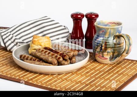 Amerikanisches Frühstück Würstchen und ein Keks mit einer Tasse Kaffee auf einer Bambusmatte Stockfoto