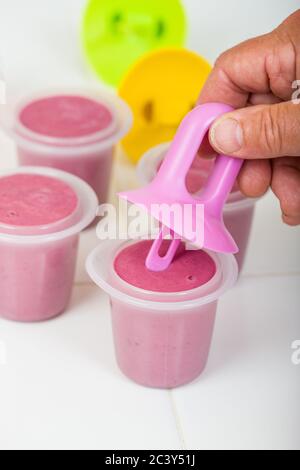 Mann Montage voll Brombeere Popsicle Formen, die auf einer weißen Fliese Arbeitsplatte ruhen Stockfoto