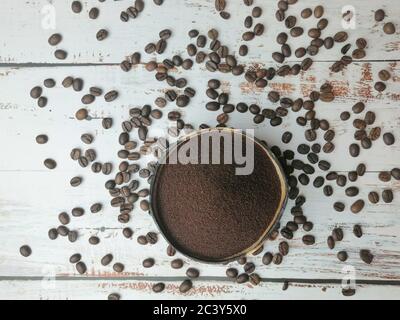 Gemahlener Kaffee in handwerklichem Behälter auf Holztisch mit Kaffeebohnen Stockfoto