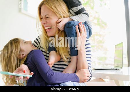 Kinder (4-5, 6-7) spielen mit der Mutter Stockfoto